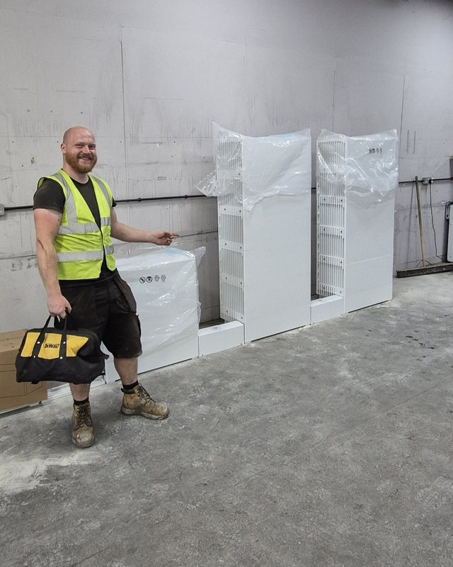 One of the team on site next to new battery units waiting to be fitted