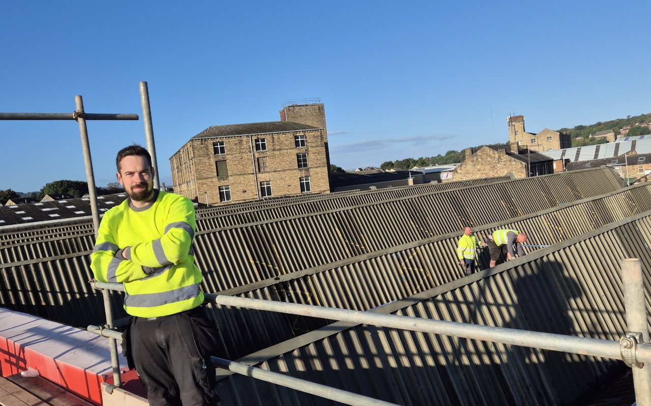 The Tokali team on the scaffold of a commercial roof job, with two installers working on the roof behind