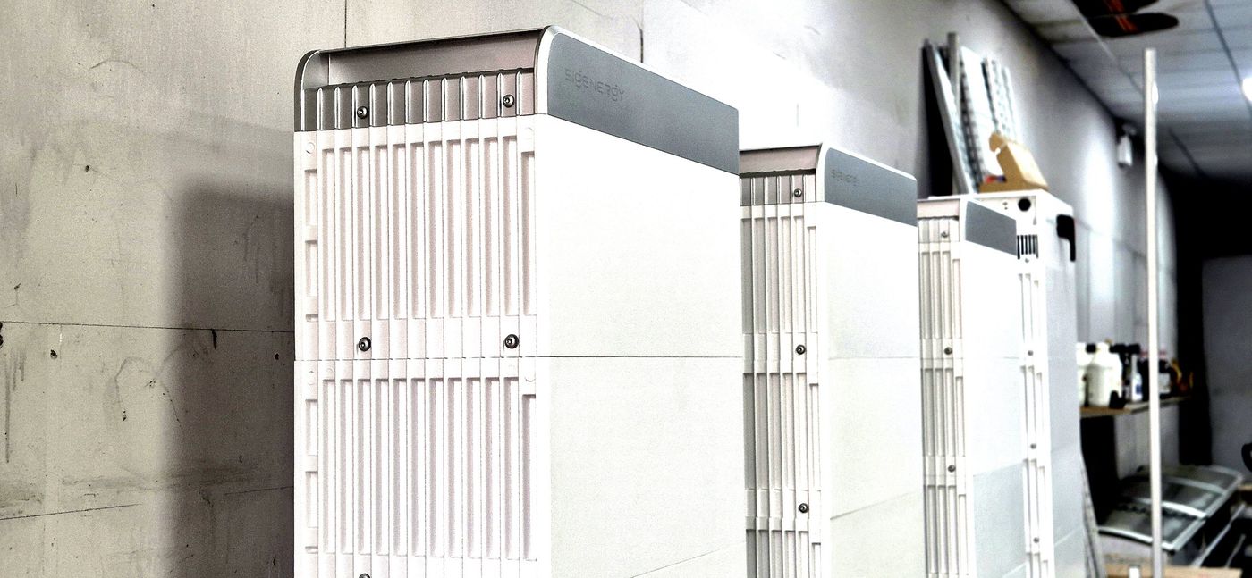 White Sigenergy battery stacks installed against a warehouse wall