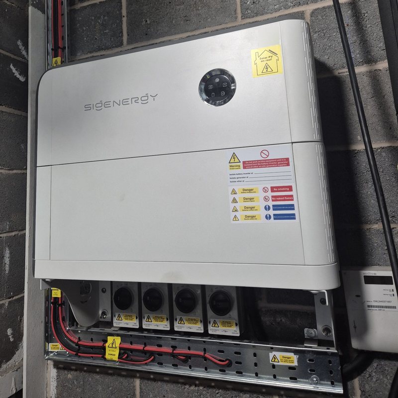 Sigenergy SigenStor energy controller and battery fitted on a block wall, with DC isolators and cable tray below